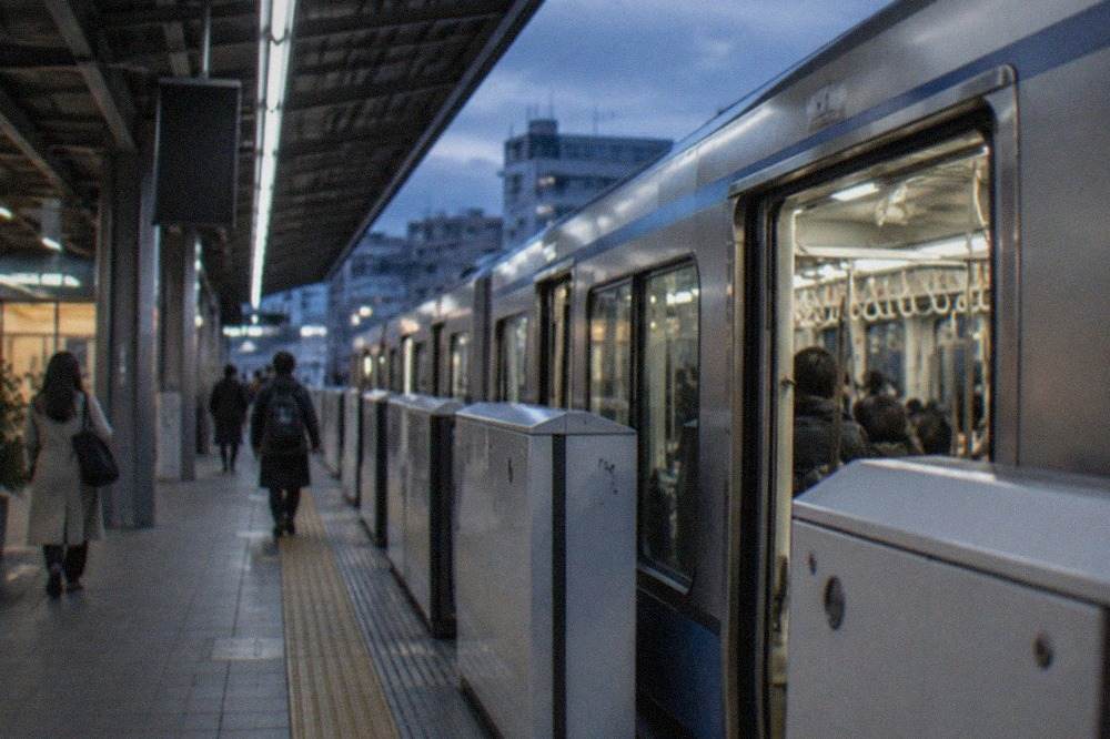 A subway platform at Fukuoka Airport station with a train waiting at the doors