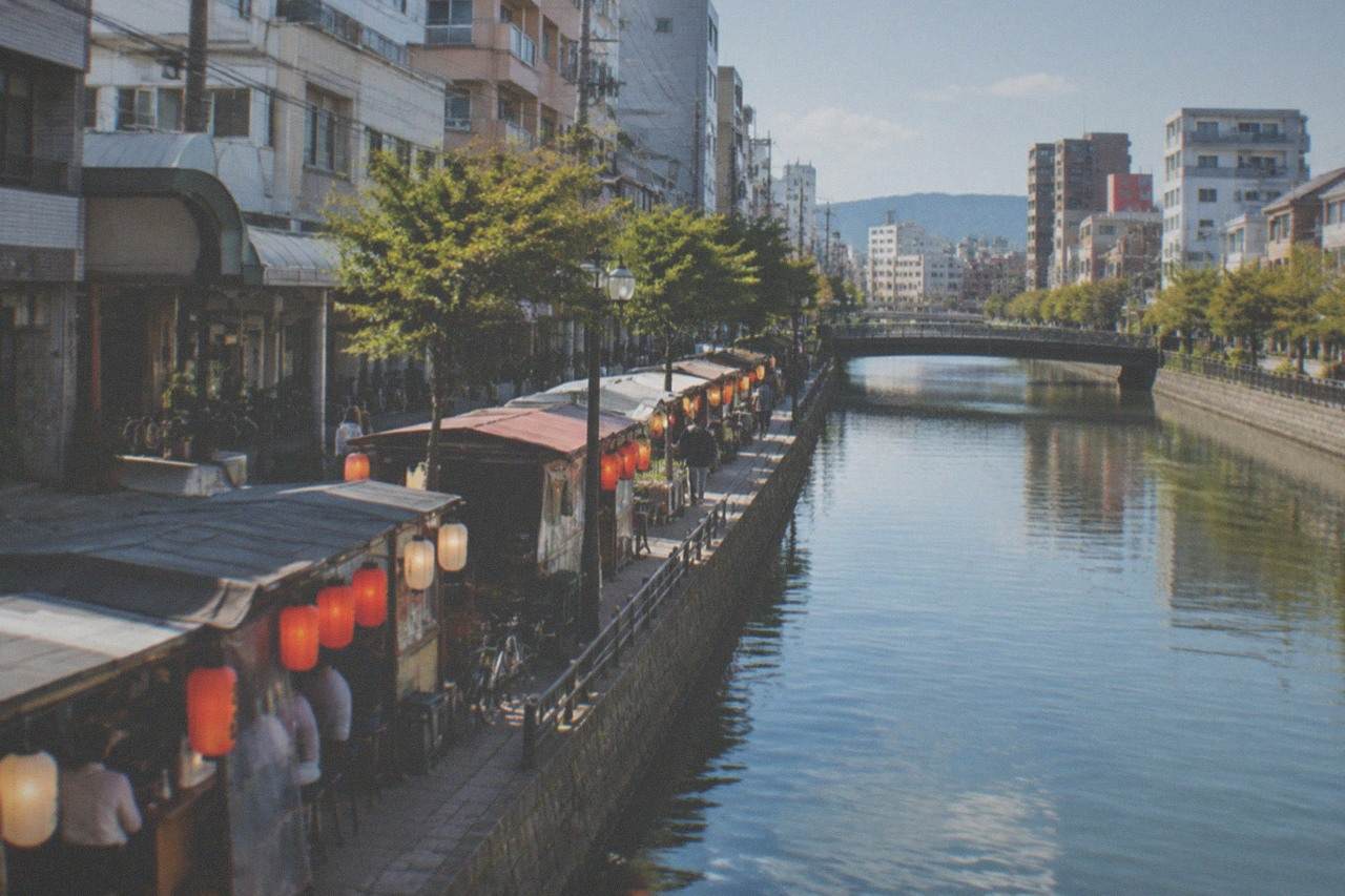 Canal-side street food stalls glowing under lanterns beside a river in Fukuoka at night