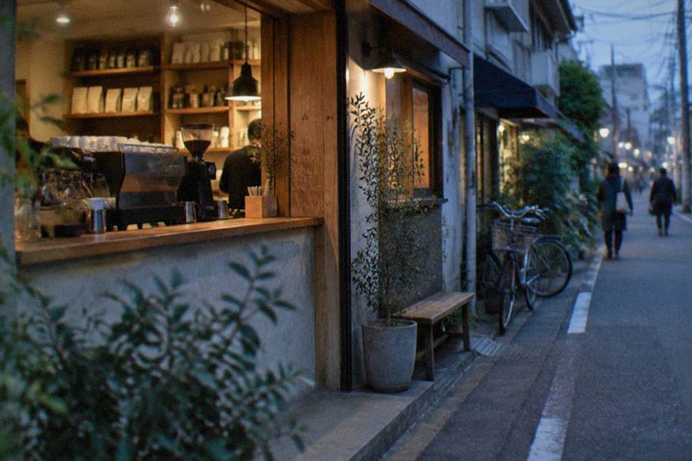 A bright cafe counter with espresso equipment and shelves of coffee bags behind the bar