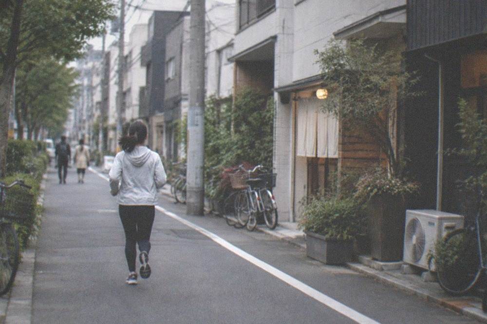 A tree-lined residential street edge with low buildings and bicycles parked along the pavement