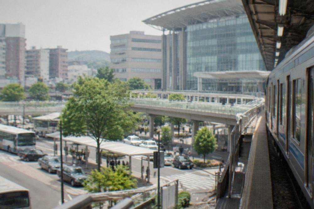 A railway platform at Hakata Station with a train waiting beside the departure board