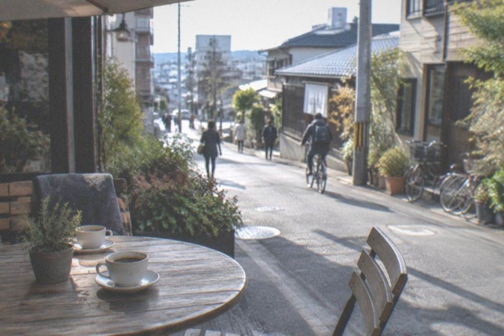 An outdoor table at an Imaizumi cafe with coffee cups and shaded seating on a side street