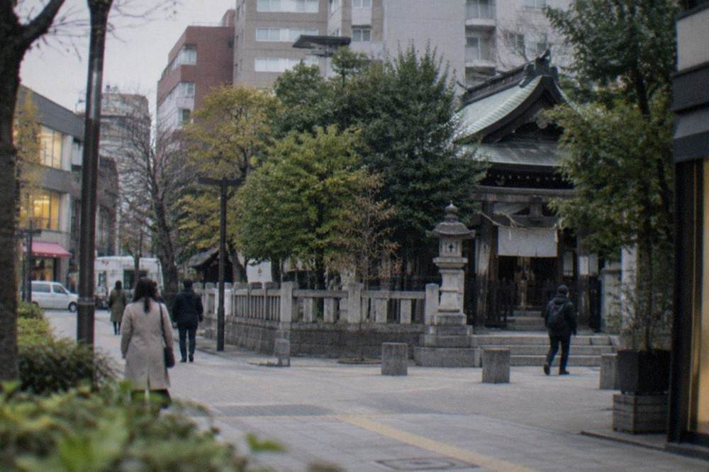 A small neighbourhood shrine with wooden buildings and stone lanterns surrounded by trees