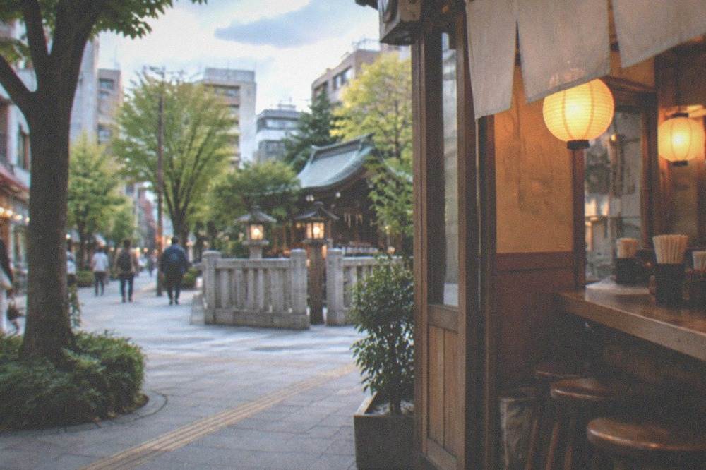 A small counter restaurant interior with wooden stools and lanterns glowing in the evening