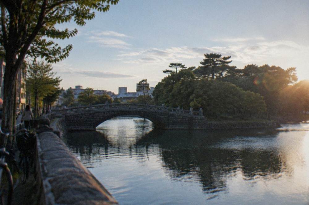 A stone bridge arcing over still water toward a small wooded island