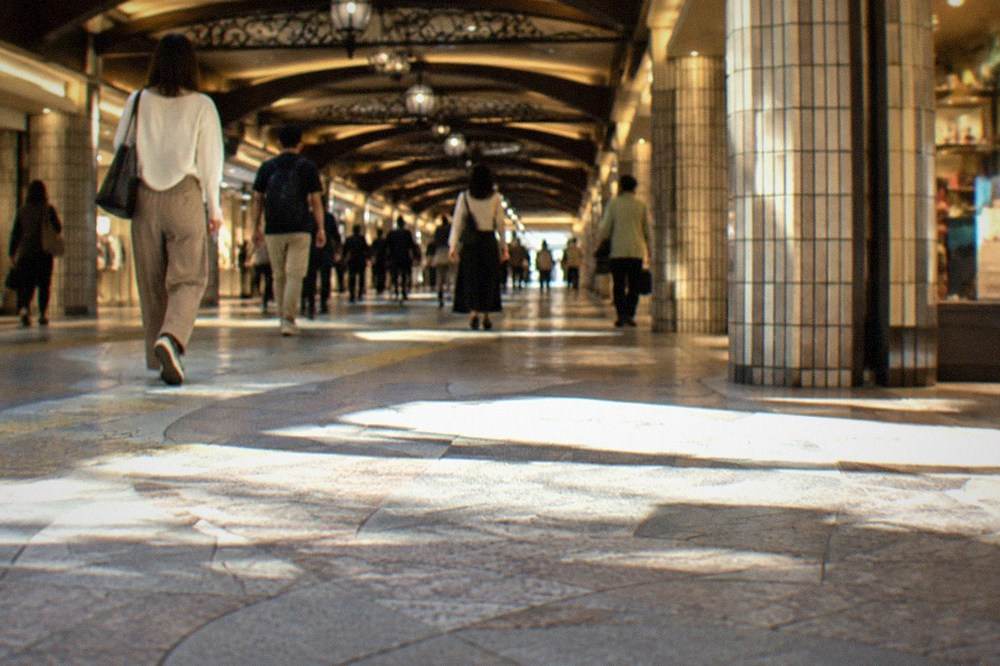Underground passage with tiled columns, illuminated shopfronts, and directional signs