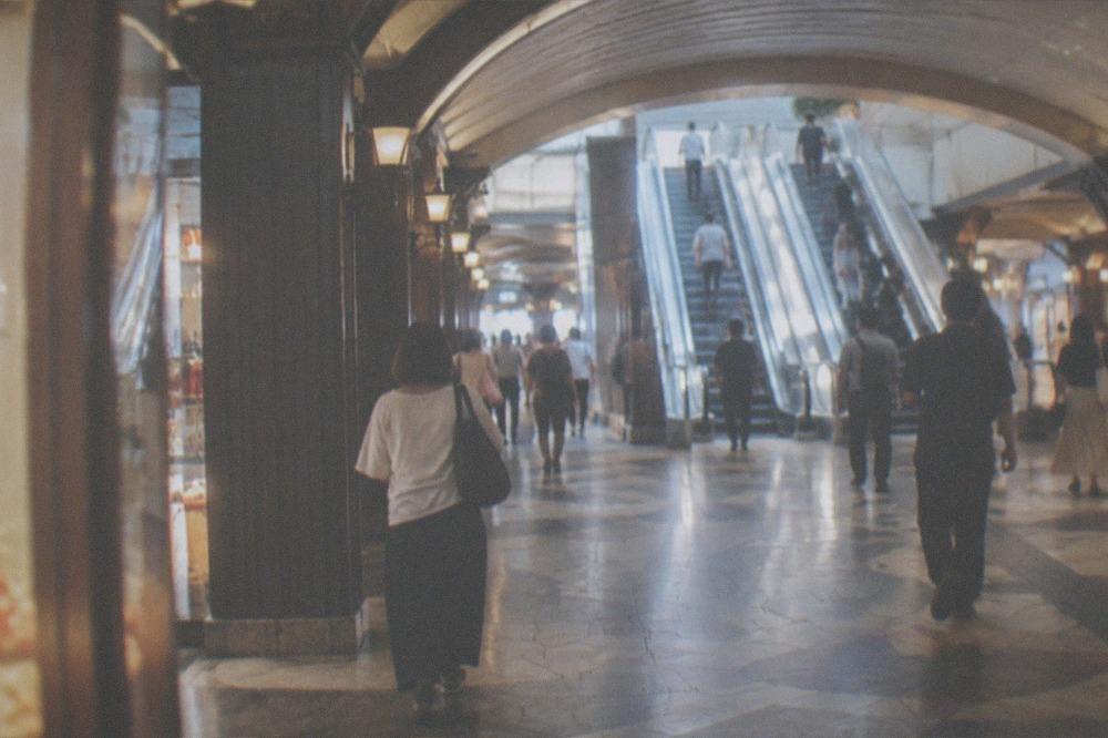 Escalator bank before an underground station concourse with passengers and overhead signage