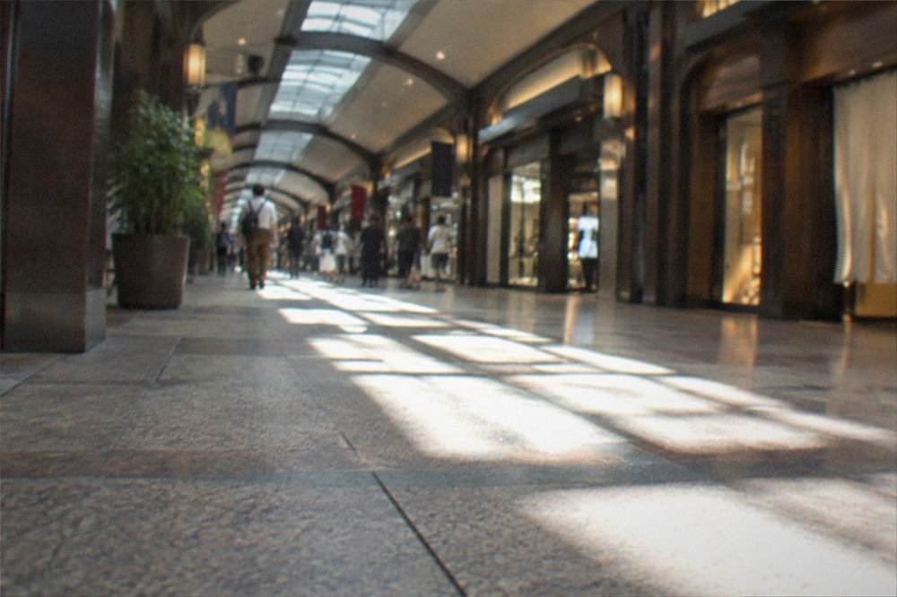 Sunlit underground mall skylight reflecting across a polished tiled concourse