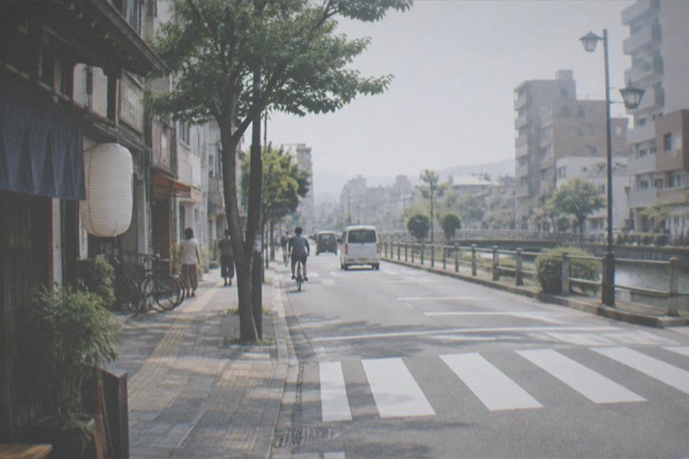 A pedestrian crossing on a wide avenue with low-rise buildings on both sides