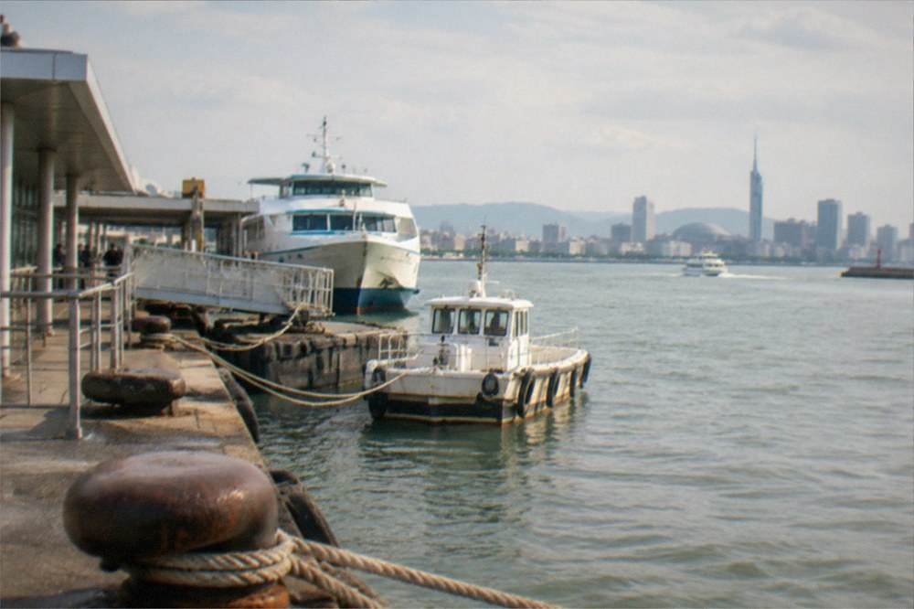 City skyline across water in late afternoon with modern towers and a tower silhouette