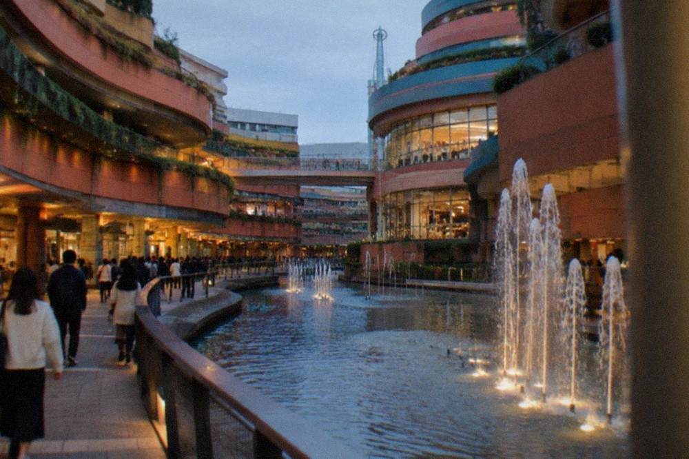 Shoppers walking along a curved canal running between terracotta building facades