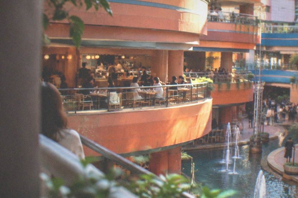 A busy restaurant level with diners at tables and a counter along a rail