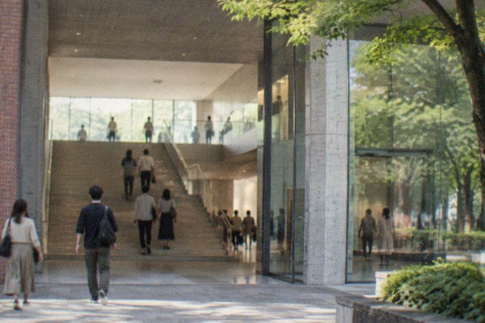 Museum entrance hall with a wide staircase and visitors walking through a bright lobby
