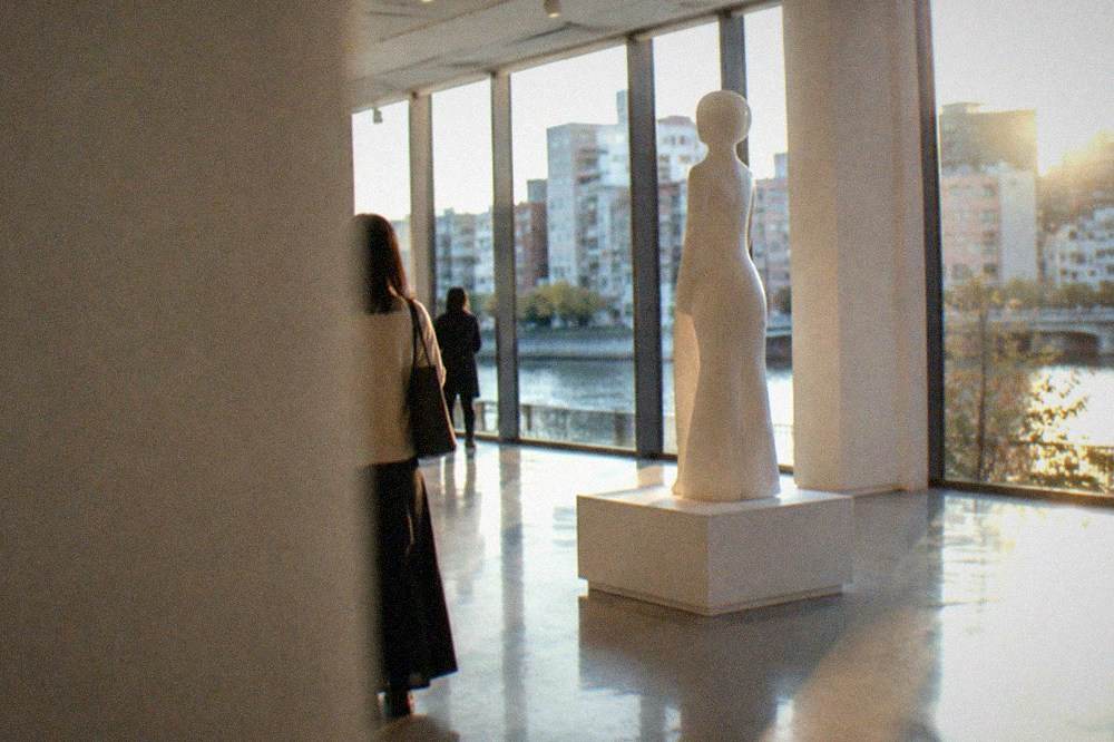 Sculpture of a stylised human figure displayed in a minimal white exhibition room