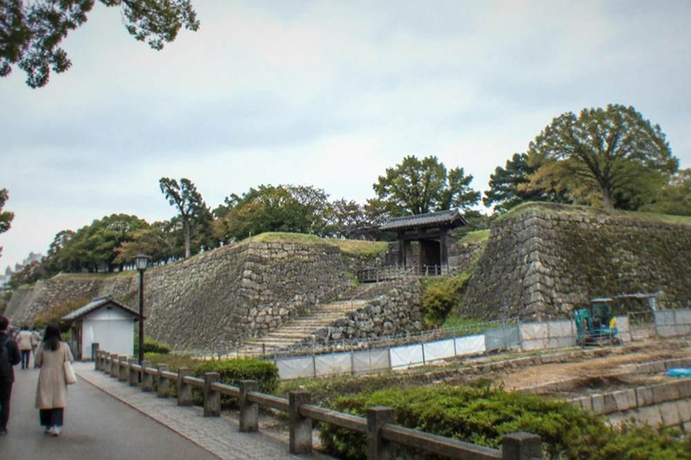Barricaded stone terrace with excavation equipment near the keep base