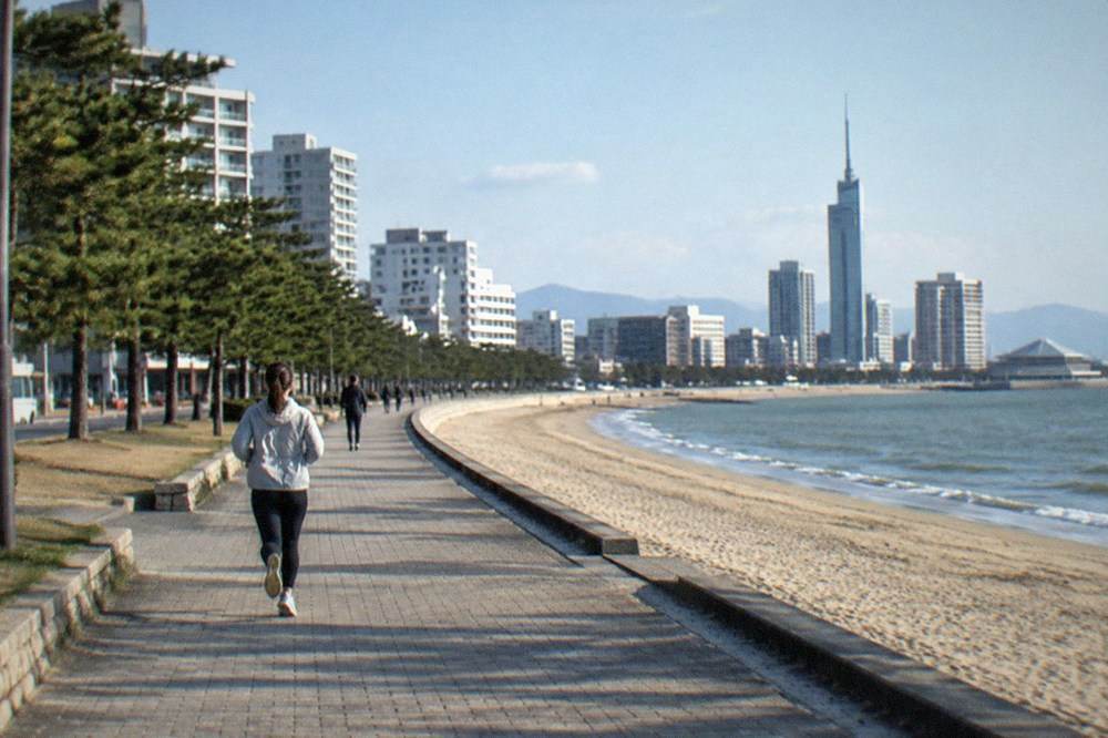 The Momochi Seaside Promenade and sandy beach with Fukuoka Tower in the background on a clear afternoon