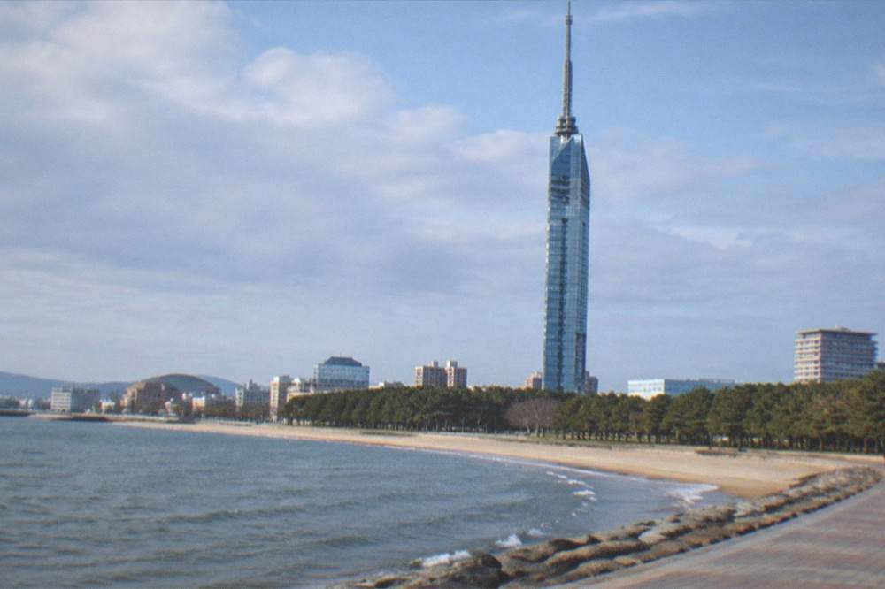 Fukuoka Tower seen from the waterfront promenade with the beach and bay in the foreground