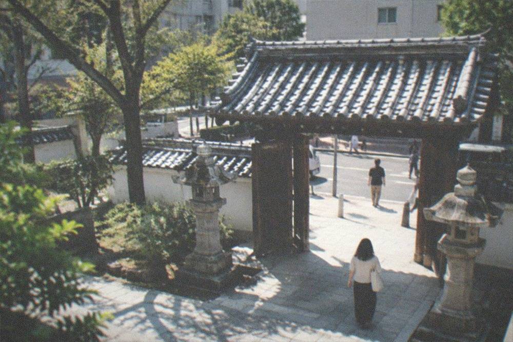 Entrance gate of a shrine in Hakata old town with stone lanterns and trees
