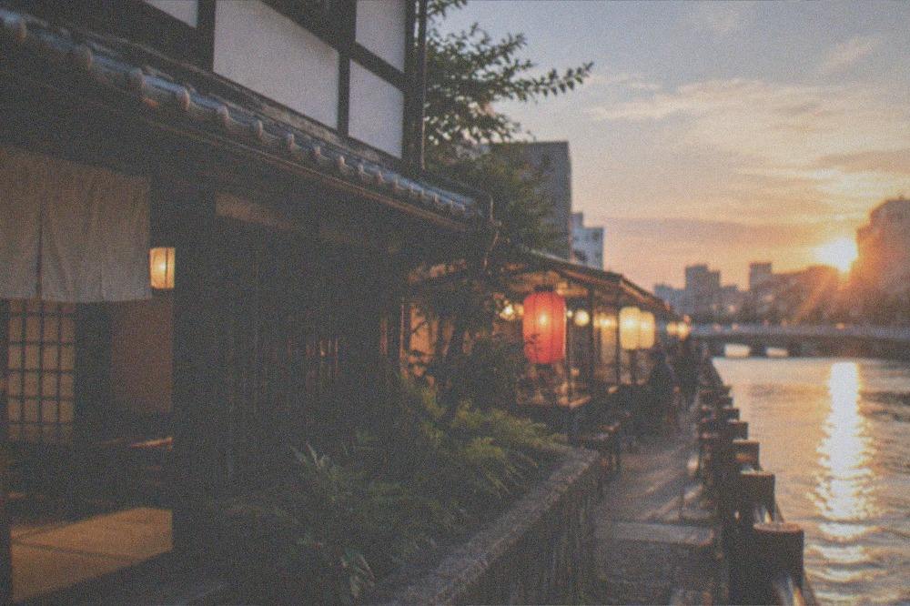 Food stall lanterns glowing beside the Naka River in the evening