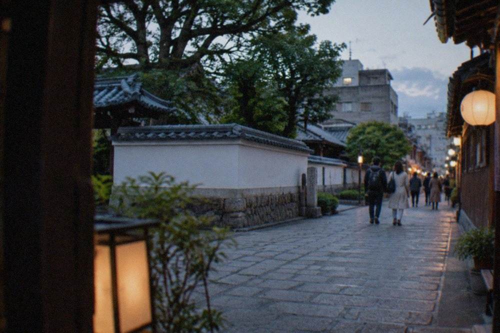 A narrow historic street in Hakata Old Town with traditional wooden building facades and lanterns in the late afternoon.