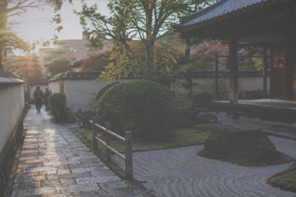 Zen temple garden corner with raked stone and a wooden fence