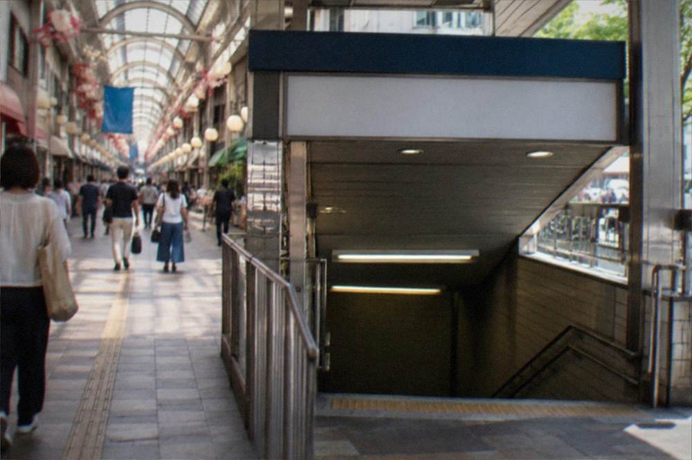 Subway station entrance on a city street with signboards above the stairwell
