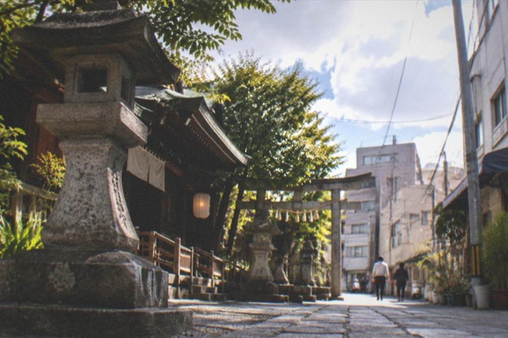 Stone lanterns and shrine buildings along a quiet path in Hakata