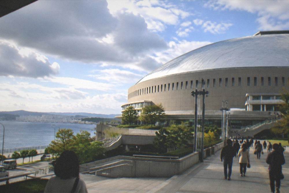 A domed stadium lit at night seen across a dark bay