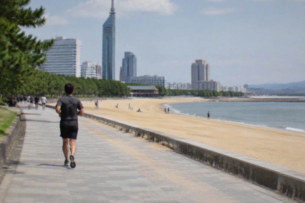 Wide sandy beach with a tall seaside tower rising behind the promenade
