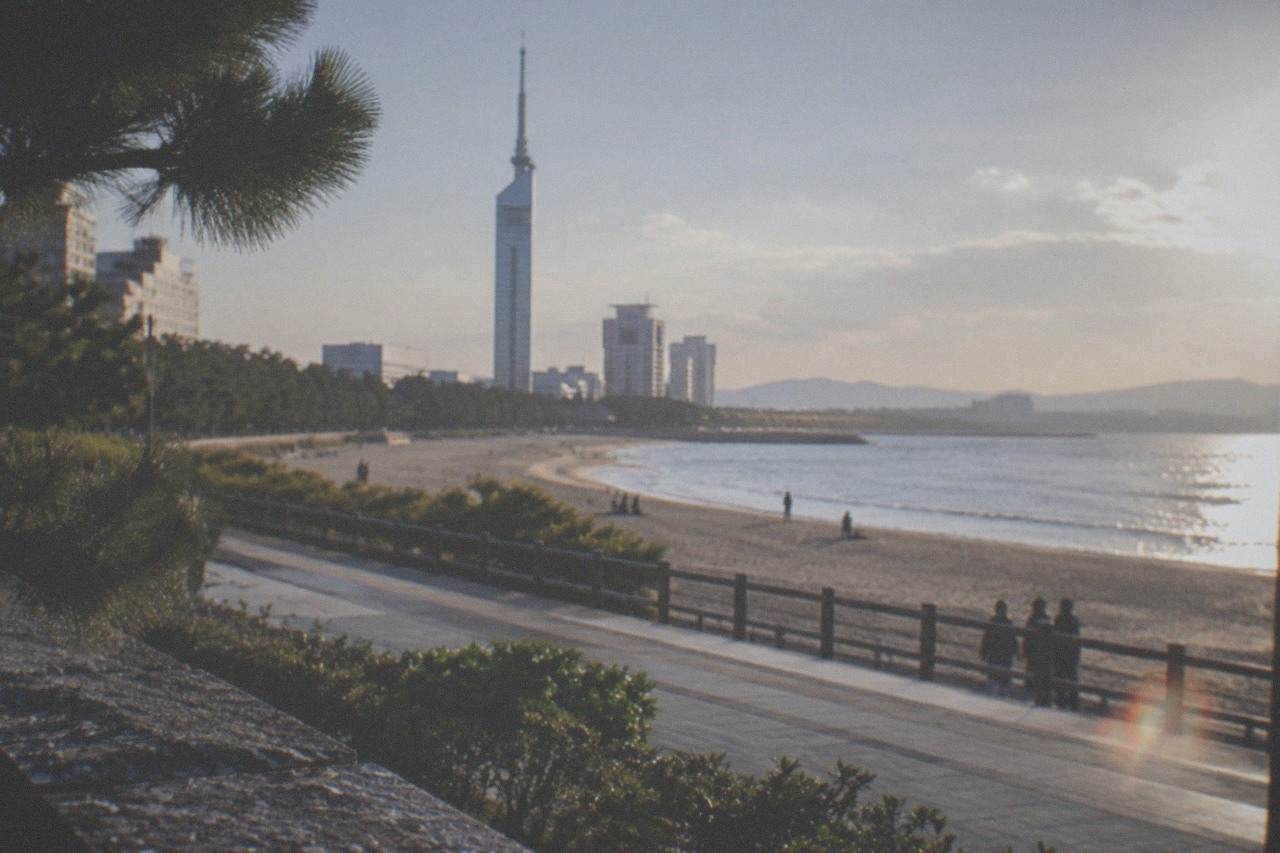 Wide sandy beach with a tall seaside tower rising behind the promenade