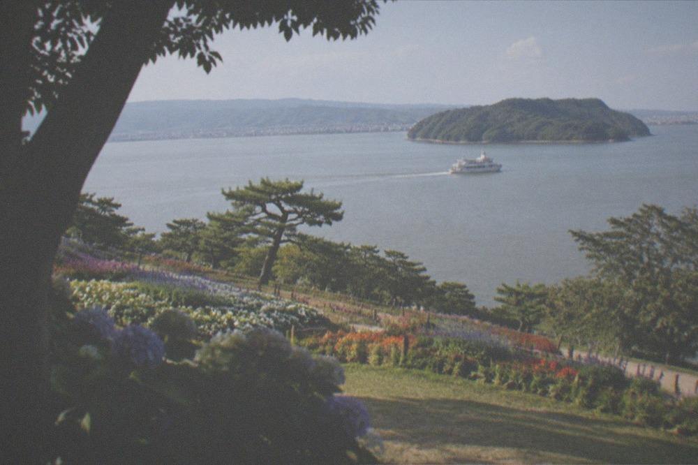 A small passenger ferry crossing calm water toward a green island
