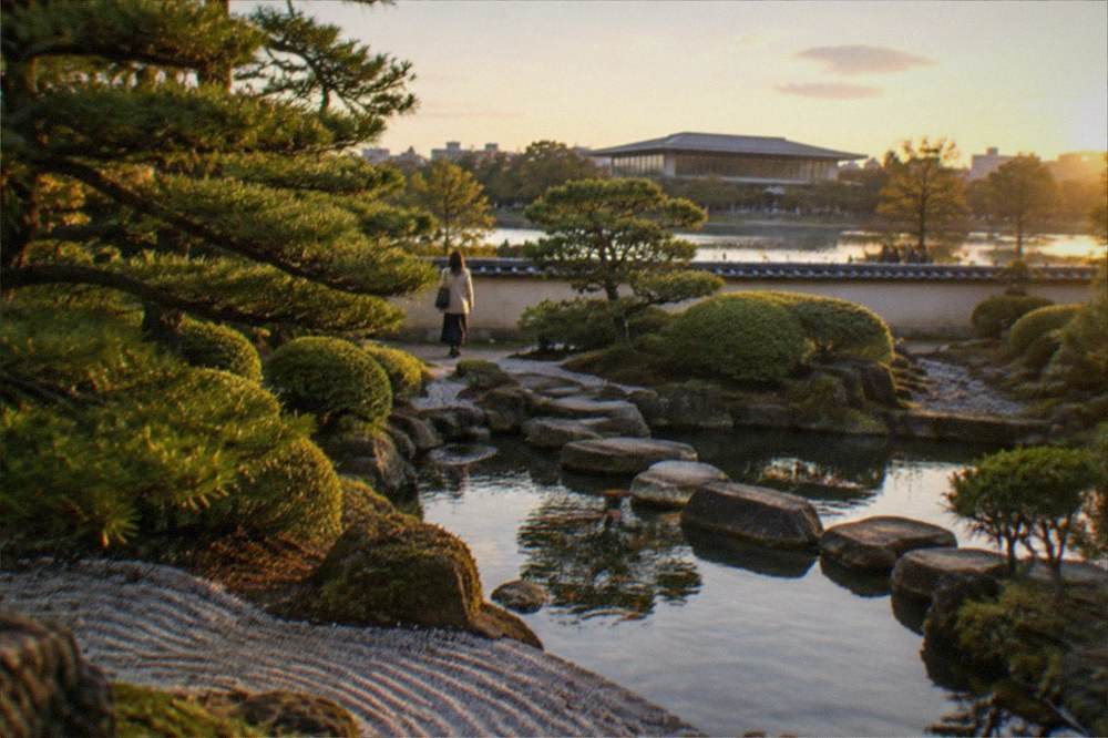 A museum building beside a park lake with trees reflected in the water