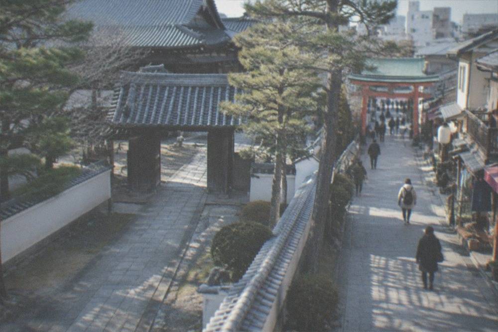 A narrow lane in the Gion district with small shopfronts and a shrine entrance