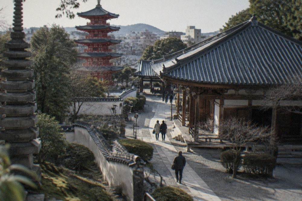 A tall stone pagoda beside a path with trees and temple walls