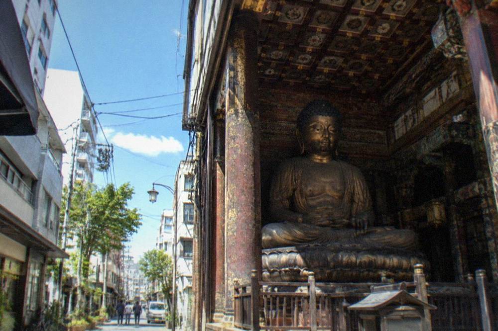 An interior hall with a very large seated Buddha figure and decorated ceiling