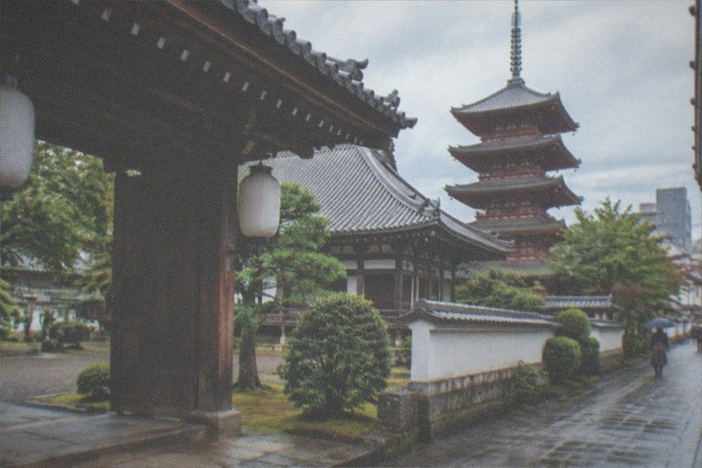 A temple gate with lanterns and a stone lane in an old neighbourhood