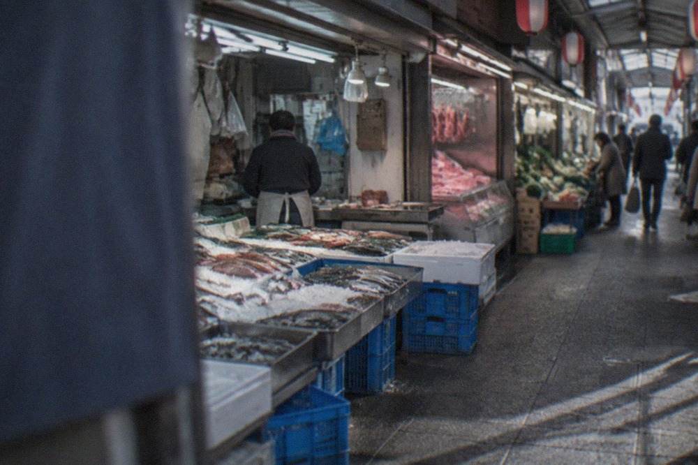 Covered shopping arcade with small fish shops and hanging lanterns in Fukuoka