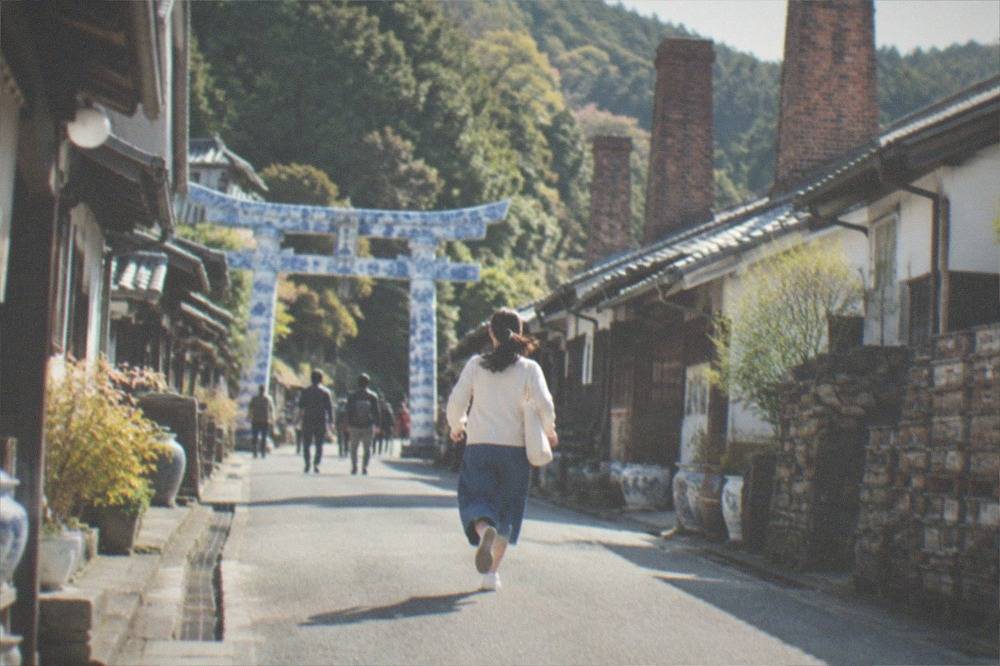 A shrine gate made entirely of white and blue porcelain standing among trees
