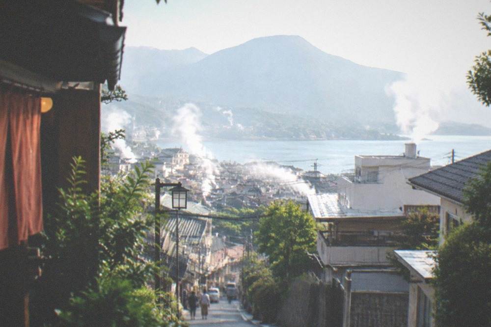 A small lake with a mountain behind it at the end of a rural town street