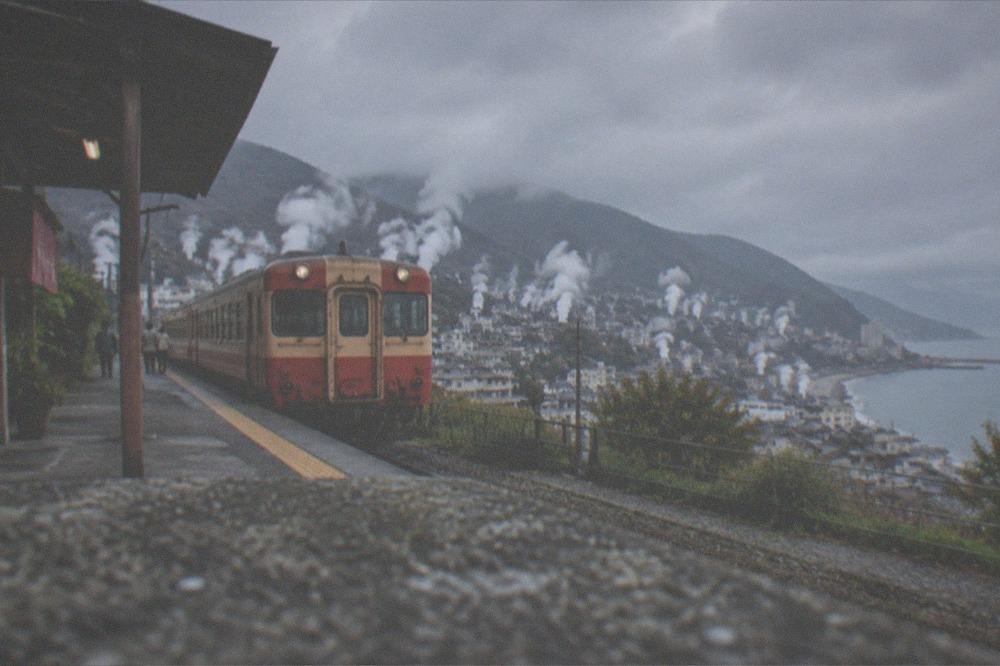A vintage styled sightseeing train waiting at a rural platform