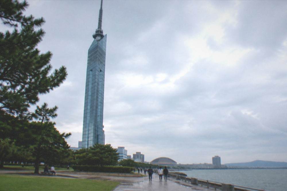 Fukuoka Tower illuminated at night above the Momochi seaside buildings