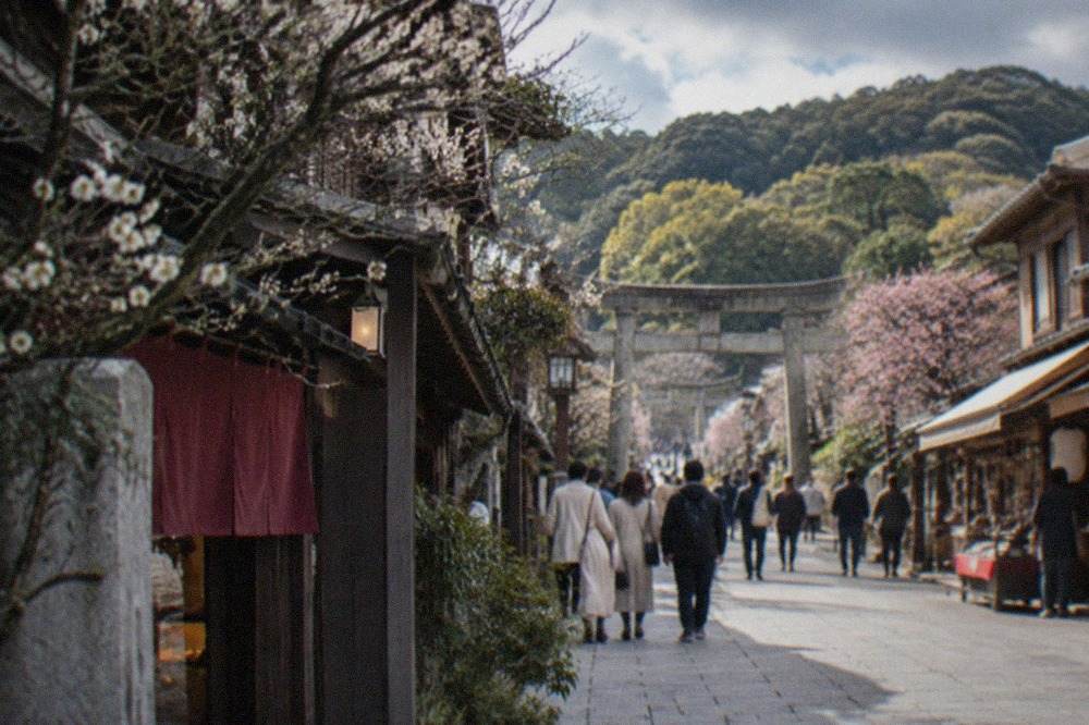 A shrine approach street lined with traditional shopfronts leading toward a torii gate