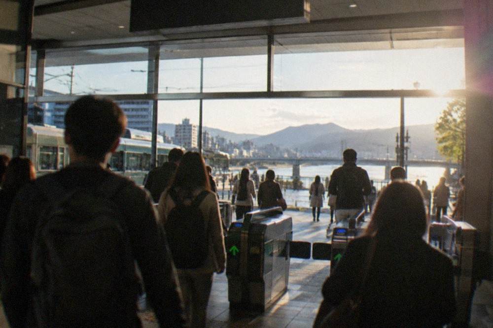 A wide station concourse with ticket gates and travellers with backpacks
