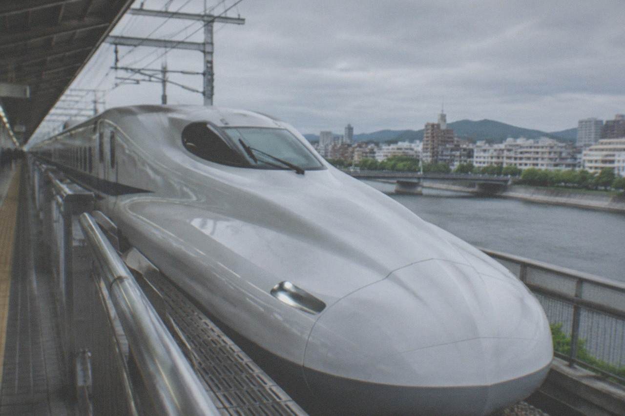 A white bullet train waiting at a covered station platform in Japan