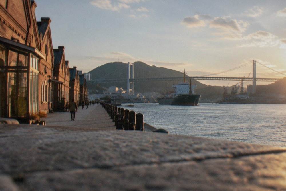 Waterfront promenade lined with red-brick Meiji-era buildings beside a calm harbour