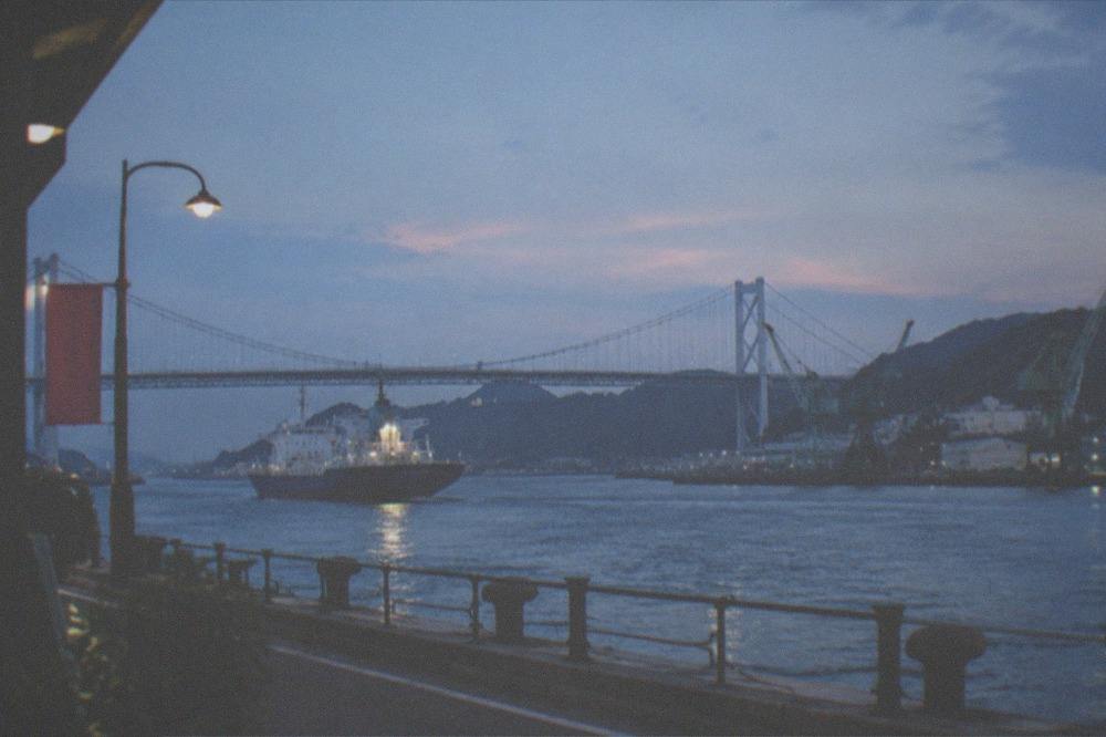 Long suspension bridge spanning a narrow strait between two islands of land at dusk