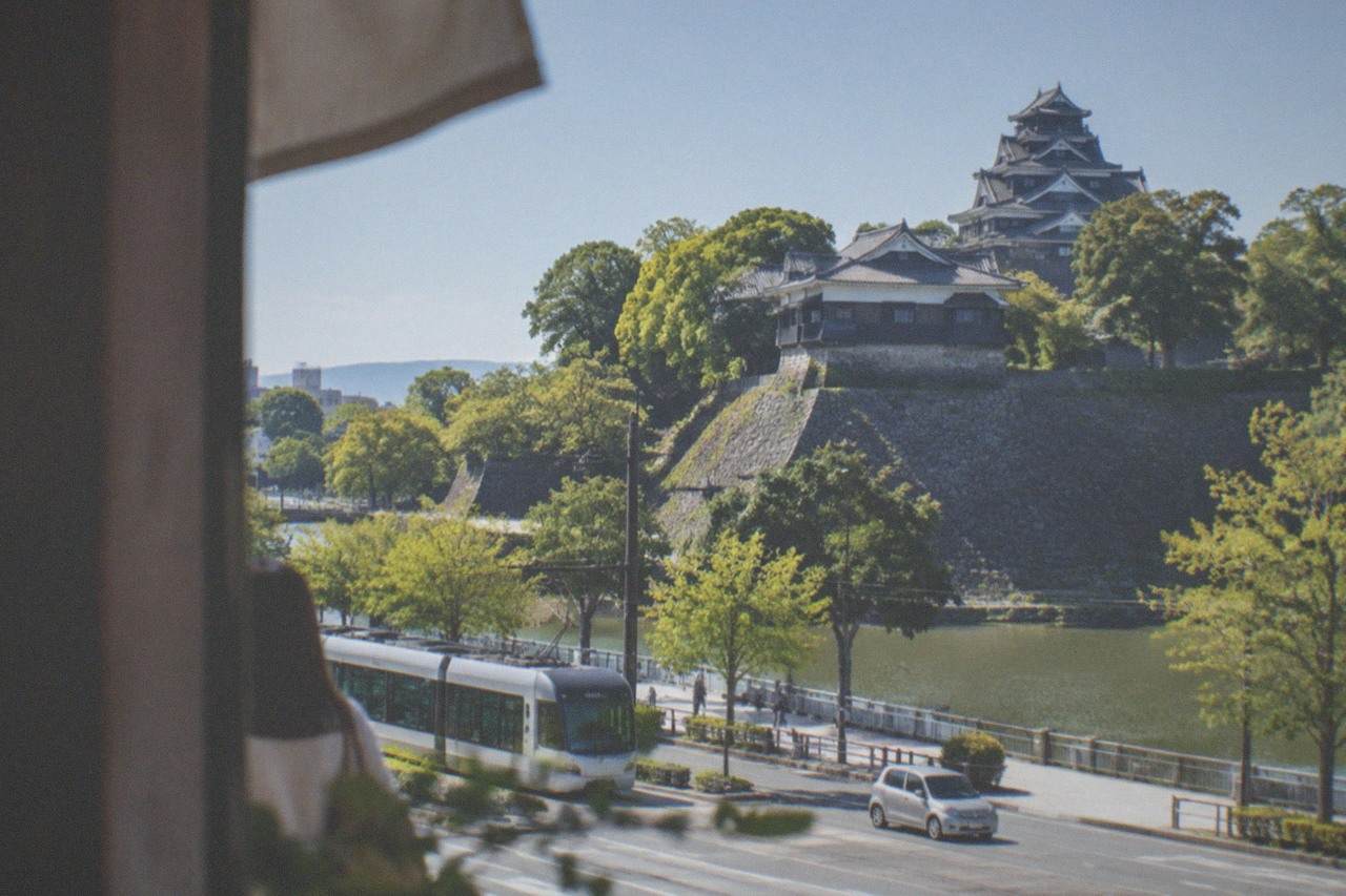 Kumamoto Castle stone walls and keep rising above tree-lined moats under a clear sky