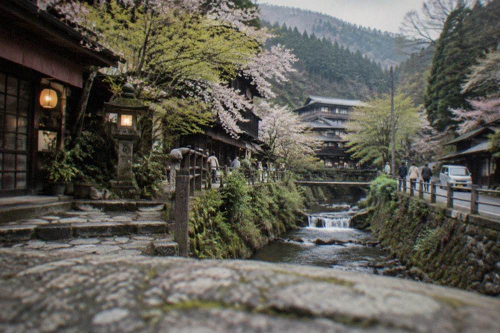 Mountain road curving through forested slopes toward a hot spring village