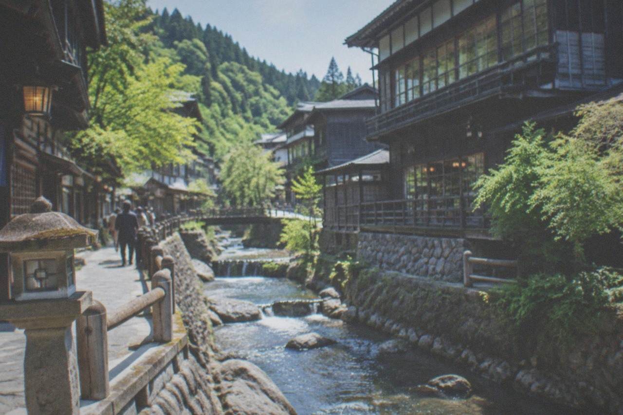 Wooden ryokan buildings along a small river in a mountain onsen village