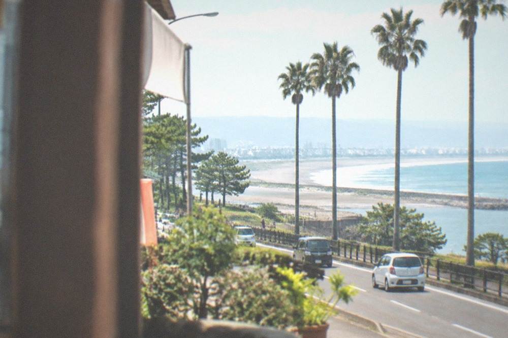 A coastal highway curving along a green shoreline with blue ocean on the horizon